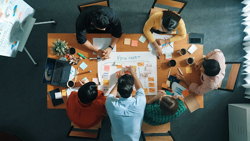 Grupo de pessoas sentadas em volta de uma mesa realizando um mapeamento de processos