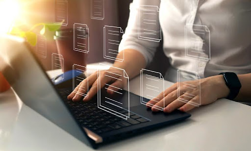 Mulher usando o notebook com alguns ícones de papel