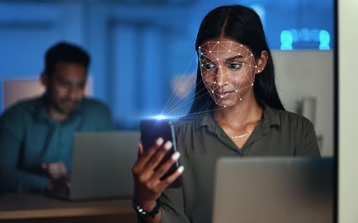 Mulher negra utilizando o celular para fazer reconhecimento facial